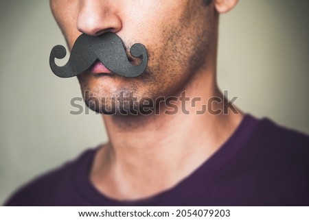 close up of a man's chin wearing a fake paper made mustache - Celebration of Movember Royalty-Free Stock Photo #2054079203