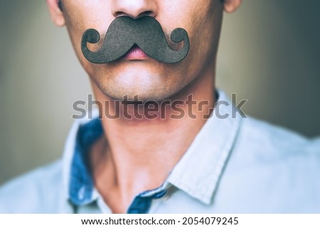 close up of a man's chin wearing a fake paper made mustache - Celebration of Movember Royalty-Free Stock Photo #2054079245