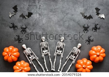 Happy Halloween holiday. Halloween decorations, skeletons, bats, pumpkins on a gray background. Halloween party greeting card mockup with copy space. Flat lay