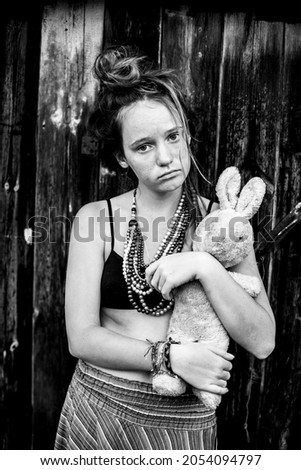 A cute teen girl with an old children's toy outdoors. Black and white photo.