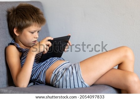 Child sitting on chair with tablet