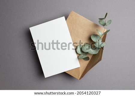 Invitation or greeting card mockup with craft envelope and natural eucalyptus twig. Card mockup with copy space. Royalty-Free Stock Photo #2054120327