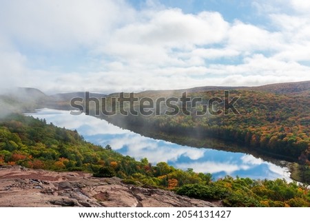 Beautiful autumn landscape with clouds reflecting in mountain lake