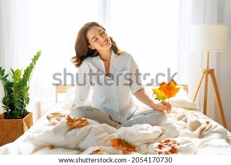 Happy young woman enjoying sunny morning on the bed.      Royalty-Free Stock Photo #2054170730