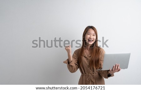 Portrait of successful asian young woman raise her right hand up after checking her e-mail on computer laptop isolated on grey background studio.