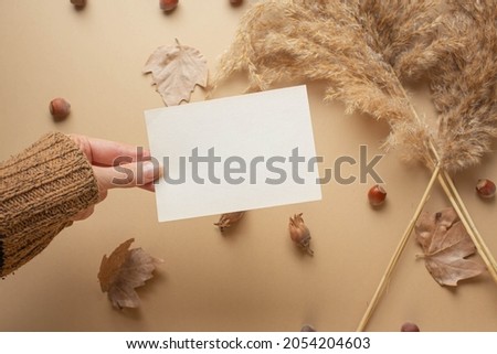 girl's hand and card in it. greeting mockup autumn mood, fall season. dry leaves, cozy atmosphere