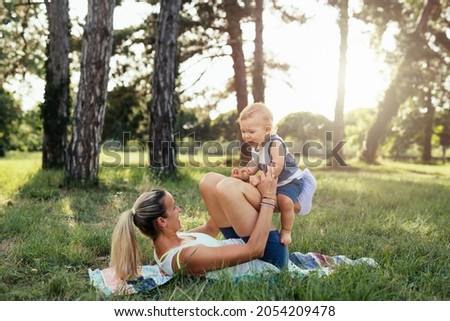 mother with her baby boy do physical exercises outdoor in park