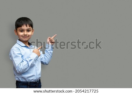 Smiling happy boy pointing finger away at copy space isolated over plain background Royalty-Free Stock Photo #2054217725