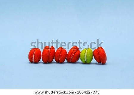 Be different concept photo from Row of macarons with green macaron between red macarons