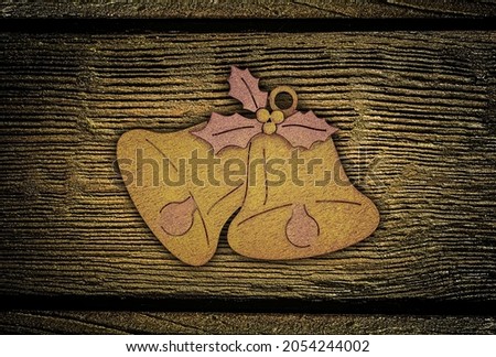Wooden Christmas bell pendant on brown board background.