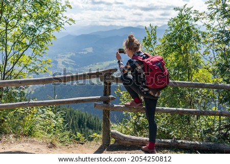 A woman, tourist is taking photo of breathtaking views of mountains and village