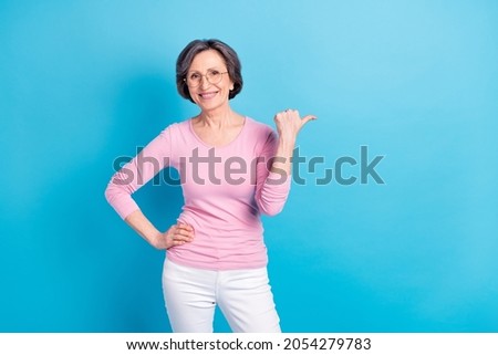 Photo of happy beautiful dreamy charming mature woman point finger copyspace advertisement isolated on blue color background