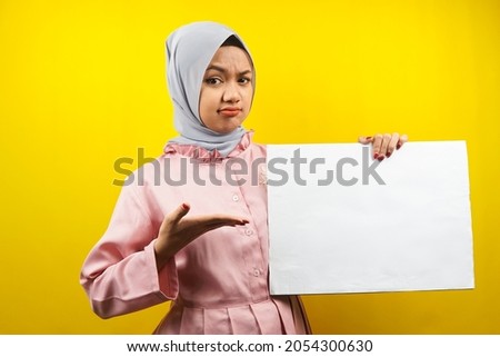 Pretty young muslim woman thinking, hand holding blank empty banner, placard, white board, blank sign board, white advertisement board, presenting something in copy space, promotion