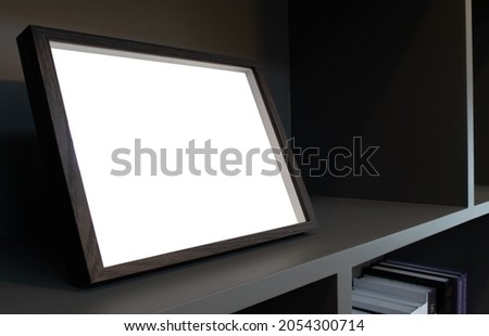 Side view or perspective of wooden picture frame with copies space or blank white screen on shelf