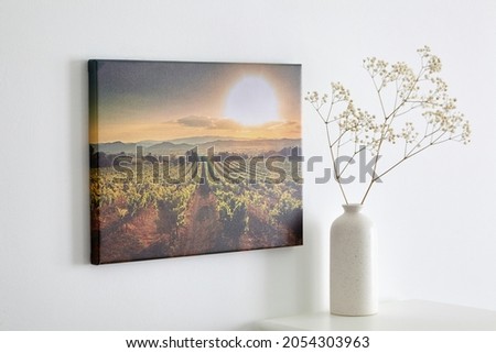 Canvas photo print with gallery wrap and flowers in vase, interior decor. Landscape photography hanging on white wall. picture with vineyard Royalty-Free Stock Photo #2054303963