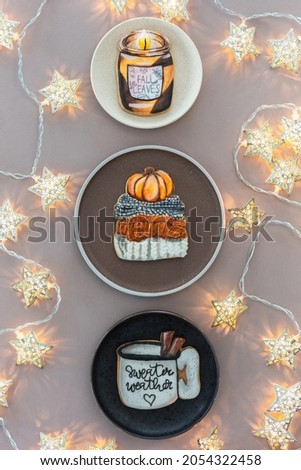 Three plates: black, brown and white with handmade gingerbread. Photographed a minimalistic composition from above on a brown background with christmas stars 