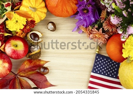 Wooden background with flowers, orange pumpkins, red leaves, chestnuts and American moisture. Thanksgiving, halloween.