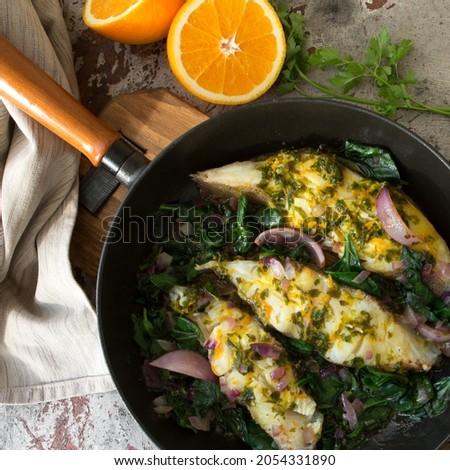 frying pan with fried halibut with orange sauce on the table