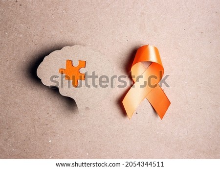 World Multiple Sclerosis Day. Orange awareness ribbon and brain symbol on a brown background. Royalty-Free Stock Photo #2054344511