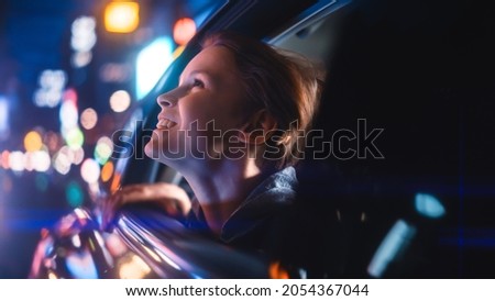 Excited Young Boy is Sitting on Backseat of a Car, Commuting Home at Night. Looking Out of the Window with Amazement of How Beautiful is the City Street with Working Neon Signs. Royalty-Free Stock Photo #2054367044