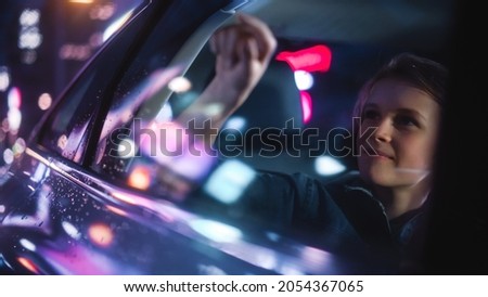 Excited Young Boy is Sitting on Backseat of a Car, Commuting Home at Night. Looking Out and Drawing on the Taxi Window while Riding the City Street with Working Neon Signs.