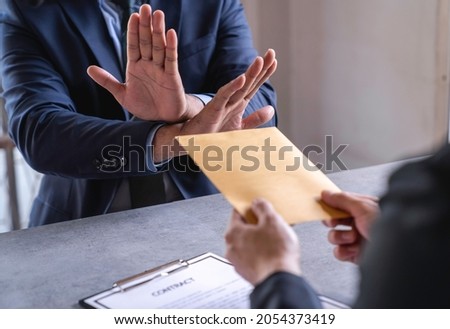Businessman refusing money that comes with agreement paper, Anti bribery, and Anti Corruption concepts. Royalty-Free Stock Photo #2054373419