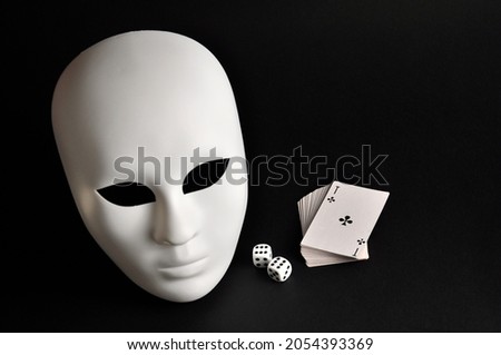 Gambler, white mask and playing cards on a black background