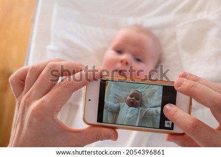 Mother make a portrait of her baby on mobile phone.