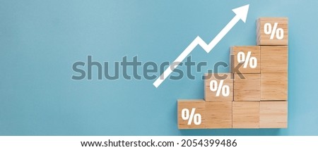 Wooden block signs and symbols with percentage sign and up arrow financial and business growth interest rates and mortgage rates interest on investment inflation concept on blue background. Royalty-Free Stock Photo #2054399486
