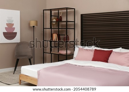 Large comfortable bed near beige wall in room. Interior design