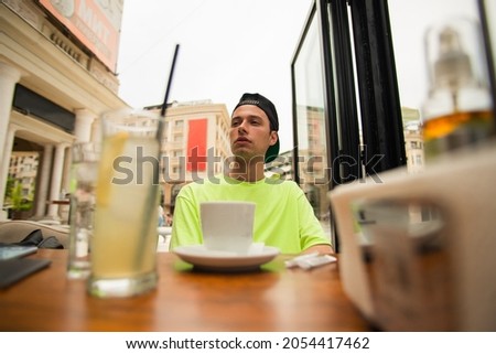 Handsome male is sitting at the coffee shop waiting for his friend