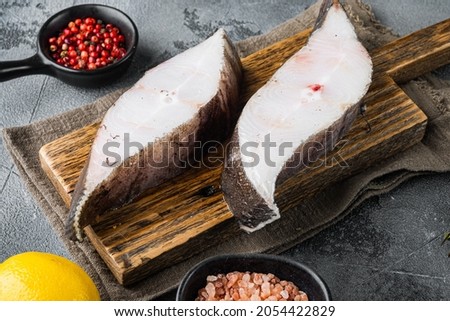 Chilled halibut steaks set, with ingredients and rosemary herbs, on gray stone table background