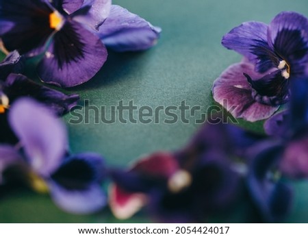 purple pansies laid out in a circle on a green background. Place for text