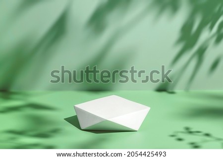 Abstract minimal nature scene - empty stage and polygonal podium on pastel mint green background and soft tree leaves shadows. Pedestal for cosmetic product and packaging mockups display presentation