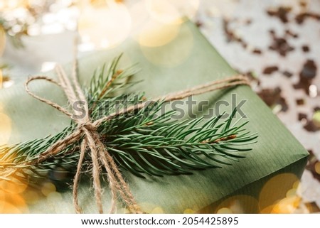 Christmas gift box wrapped in green kraft paper and decorated with pine tree branch