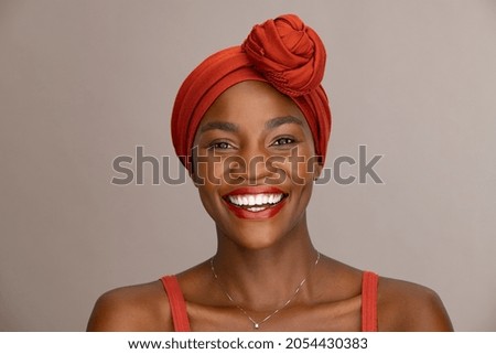 Portrait of beautiful african woman with red headscarf against brown background with copy space. Cheerful black mid woman wearing ethnicity headband. Mature happy lady with traditional clothes. Royalty-Free Stock Photo #2054430383
