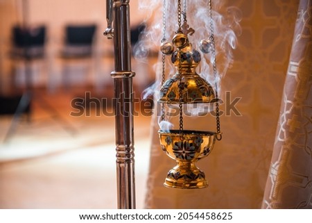 golden censer lit and smoke coming out during a mass in a church Royalty-Free Stock Photo #2054458625