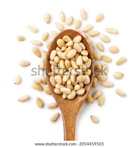 Pine nut in a wooden spoon and scattered close-up on a white background. Top view Royalty-Free Stock Photo #2054459501