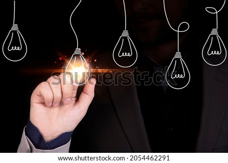 Businessman hand touching glowing lightbulb among lamp does not light for selective creative smart thinking ideas and innovation concept. High quality photo