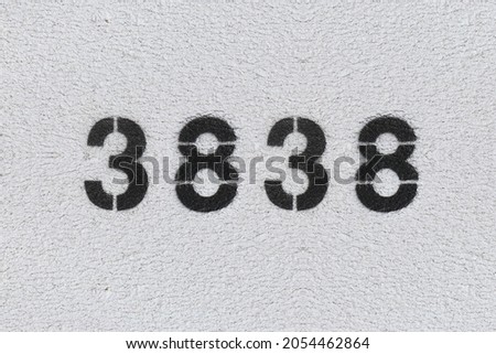 Black Number 3838 on the white wall. Spray paint. Number three thousand eight hundred and thirty eight.