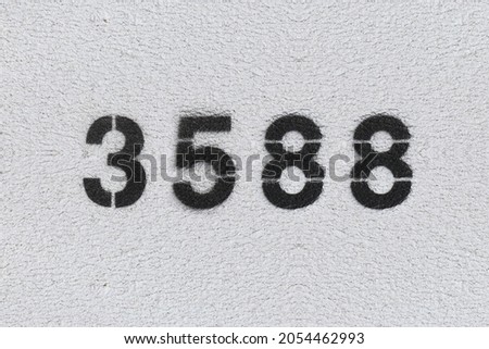 Black Number 3588 on the white wall. Spray paint. Number three thousand five hundred and eighty.