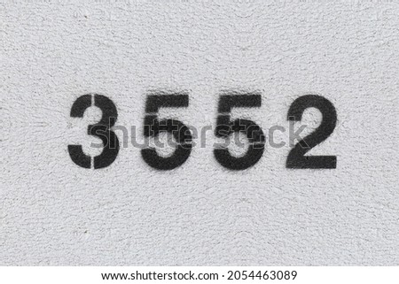 Black Number 3552 on the white wall. Spray paint. Number three thousand five hundred fifty two.