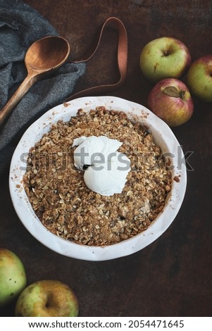 Fresh hot homemade apple crisp or crumble with crunchy streusel topping topped with vanilla bean ice cream. Selective focus with blurred background and foreground. 