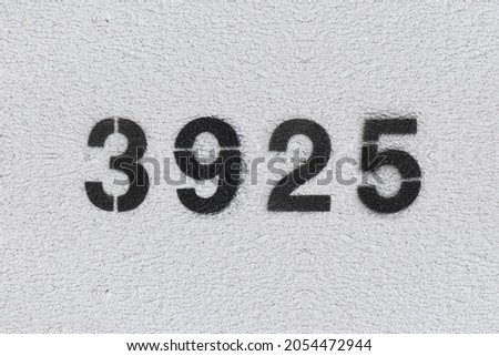 Black Number 3925 on the white wall. Spray paint. Number three thousand nine hundred and twenty five.