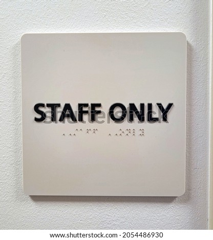 "Staff Only" white sign with black letters and braille in office hospital commercial setting