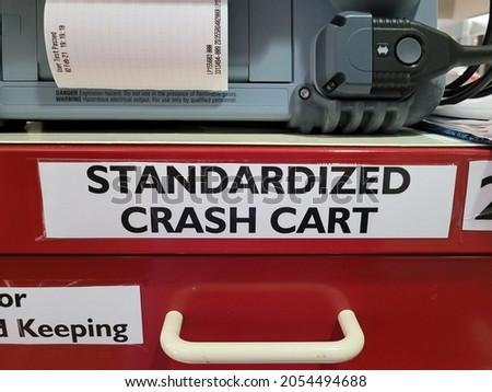 "Standardized Crash Cart" white sign on red supply cart in Intensive Care Unit Hospital setting 