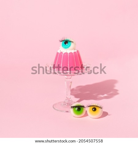 Creative layout with pink jelly on dish with eyeball figurines on pastel pink background. Halloween retro style aesthetic idea. Minimal 70s or 80s food concept.