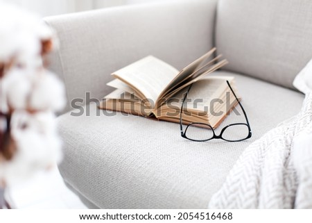 Reading book at home. Opened paper pages and spectacles on couch Royalty-Free Stock Photo #2054516468