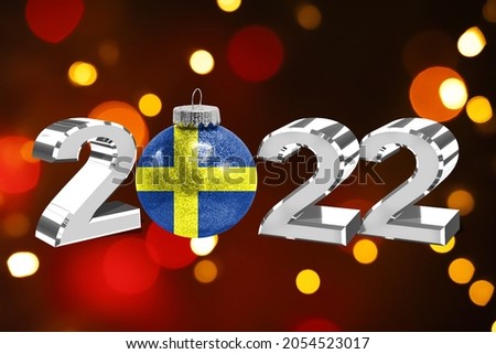 Colorful blurred background and applied the flag of Sweden on the New Year's toy. New Year 2022 Celebration