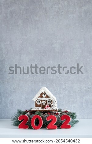 Gingerbread house and Inscription 2022. Merry Christmas background, copy space. Light gray wall on background.